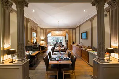 a restaurant with long tables and chairs in a room at Hotel de Flandre Ghent in Ghent