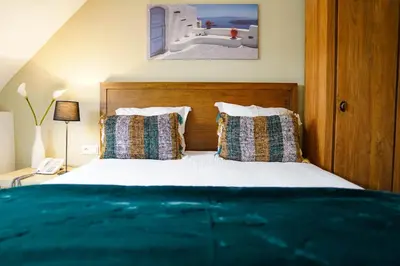 a bedroom with a bed with a wooden headboard and pillows at Hotel de Flandre Ghent in Ghent