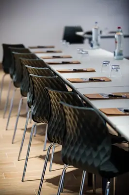 a row of tables with black chairs in a room at Hotel de Flandre Ghent in Ghent