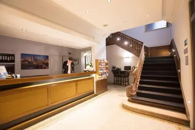 a man is standing at a counter in a lobby at Hotel de Flandre Ghent in Ghent