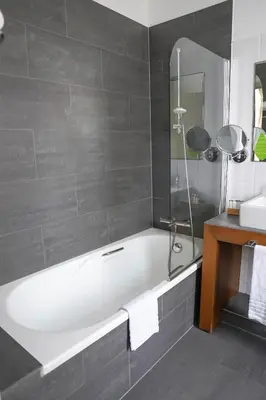 a bathroom with a white bath tub and a sink at Hotel de Flandre Ghent in Ghent