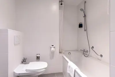 a white bathroom with a toilet and a bath tub at Holiday Inn Brussels Schuman by IHG in Brussels