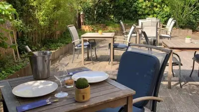 a wooden table with plates and wine glasses on a patio at Holiday Inn Brussels Schuman by IHG in Brussels