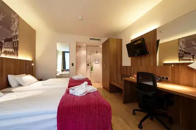 a hotel room with a bed and a desk and a chair at Holiday Inn Brussels Schuman by IHG in Brussels