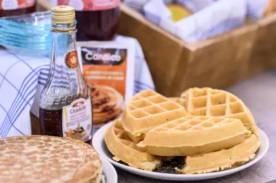 a plate of waffles and a sandwich and a bottle of syrup at Holiday Inn Brussels Schuman by IHG in Brussels