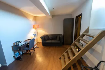 a living room with a couch and a stair case at Résidence-Hotel Le Quinze Grand Place Brussels in Brussels