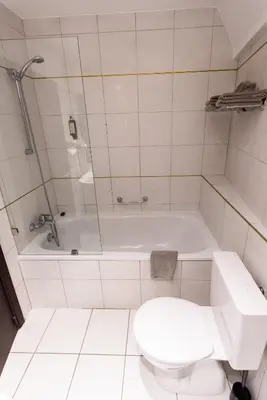 a white bathroom with a toilet and a tub at Résidence-Hotel Le Quinze Grand Place Brussels in Brussels