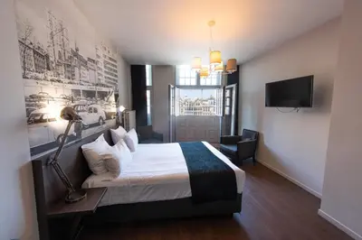 a hotel room with a bed with a lamp and a tv at Résidence-Hotel Le Quinze Grand Place Brussels in Brussels