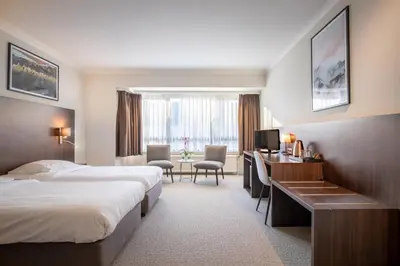 a hotel room with two beds and a desk at Hotel Carlton in Ghent
