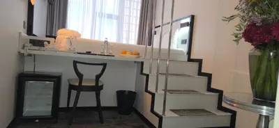 a bathroom with a shelf and a chair and a mirror at Hotel Floris Arlequin Grand-Place in Brussels