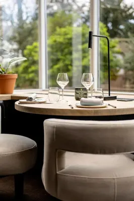 a table with two wine glasses and a chair at The Hotel Brussels in Brussels