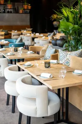 a row of tables in a restaurant with white chairs at The Hotel Brussels in Brussels