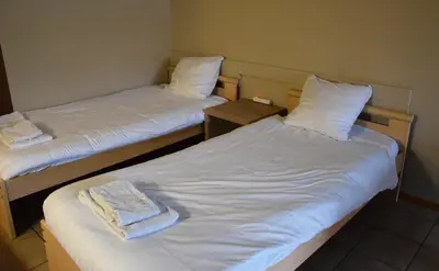 two beds in a room with white sheets and towels at Condo Gardens Antwerp in Antwerp
