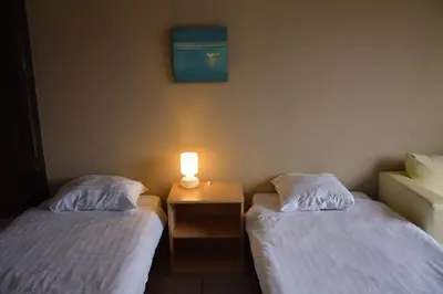 two beds in a room with a lamp on a table at Condo Gardens Antwerp in Antwerp