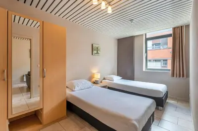 a hotel room with two beds and a window at Condo Gardens Brussels in Brussels