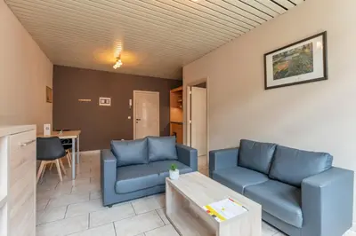 a living room with blue couches and a table at Condo Gardens Brussels in Brussels