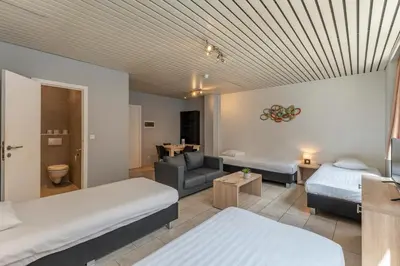a hotel room with two beds and a couch at Condo Gardens Brussels in Brussels
