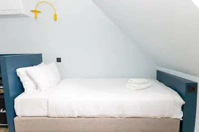 a bed with white sheets and a blue headboard at P6 Antwerp in Antwerp