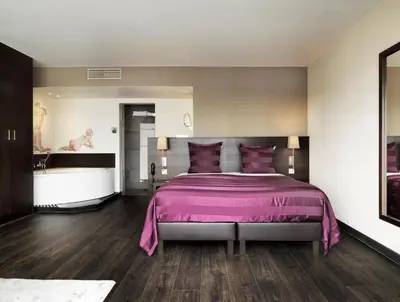 a bedroom with a pink bed and a bath tub at Hotel Harmony in Ghent