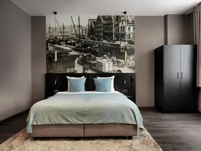 a bedroom with a large bed with a painting on the wall at Hotel Harmony in Ghent