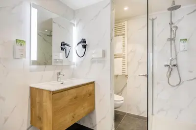 a bathroom with a sink and a shower and a toilet at Hotel Louise in Brussels