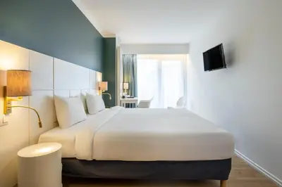 a bedroom with a large white bed and a table at Hotel Louise in Brussels
