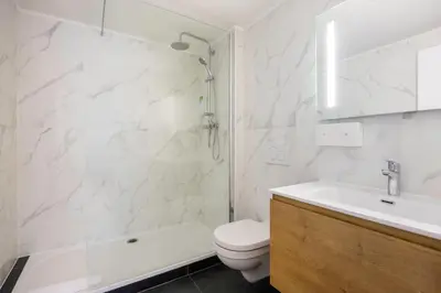 a white bathroom with a shower and a toilet at Hotel Louise in Brussels