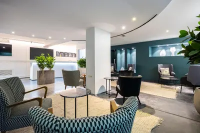 a waiting room with chairs and tables and blue walls at Hotel Louise in Brussels
