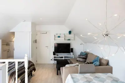 a white living room with a couch and a tv at Studio Apartment Alba in La Hulpe