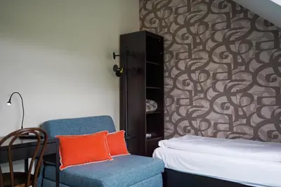 a room with a bed and a chair and a wall at Hotel Prins van Oranje in Diest