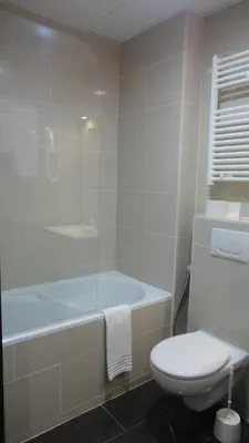a bathroom with a tub and a toilet and a sink at Hotel L'auberge Du Souverain in Brussels