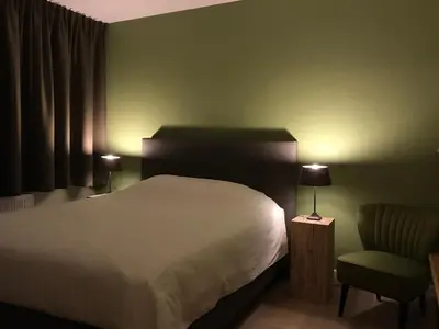 a bedroom with a white bed and a chair at B&B Garden55 in Mechelen