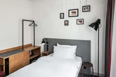 a bedroom with a bed and a desk and pictures on the wall at pentahotel Leuven in Leuven
