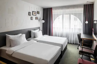 a hotel room with two beds and a desk at pentahotel Leuven in Leuven