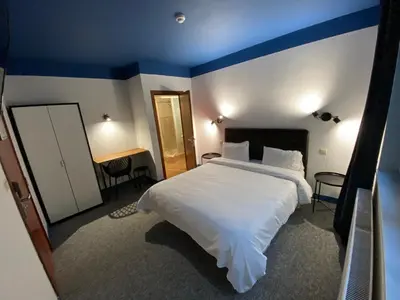 a bedroom with a large white bed with a blue ceiling at Hotel Windsor in Brussels