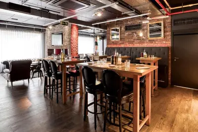 a restaurant with wooden tables and black chairs at Pentahotel Brussels Airport in Diegem