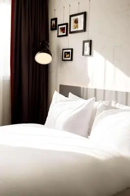 a bedroom with a white bed with pictures on the wall at Pentahotel Brussels Airport in Diegem
