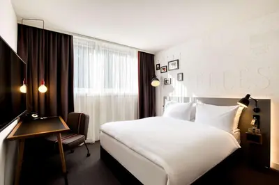 a hotel room with a white bed and a chair at Pentahotel Brussels Airport in Diegem