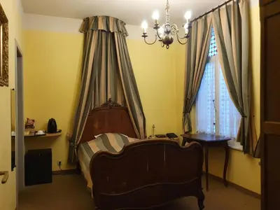 a bedroom with a bed and a chair and a chandelier at Erasmus Hotel in Ghent