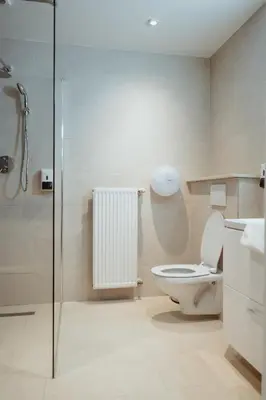a bathroom with a toilet and a glass shower at Hotel Le Centenaire Brussels Expo in Brussels