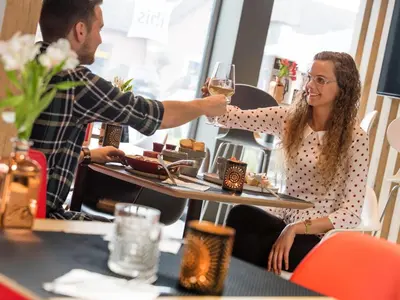 a man serving a woman a glass of wine at a table at ibis Aalst in Aalst