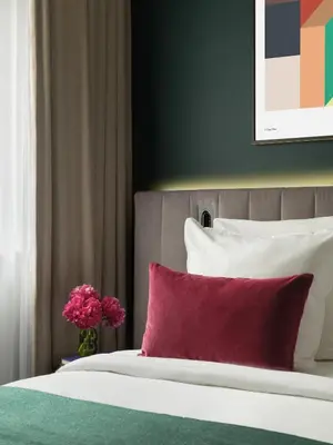 a bed with a red pillow and a vase of flowers at Numa Brussels Royal Galleries in Brussels