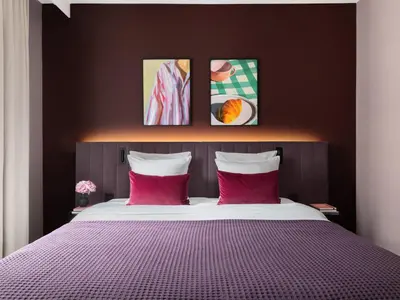 a bedroom with a large bed with two pink pillows at Numa Brussels Royal Galleries in Brussels