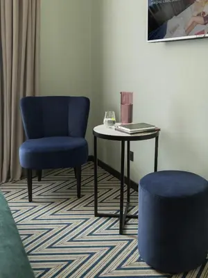 a room with a table and a blue chair and a stool at Numa Brussels Royal Galleries in Brussels