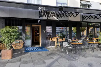 a restaurant with tables and chairs in front of a building at Hotel Indigo Antwerp City Centre by IHG in Antwerp