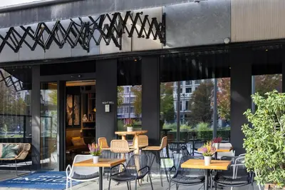 a group of tables and chairs in front of a building at Hotel Indigo Antwerp City Centre by IHG in Antwerp