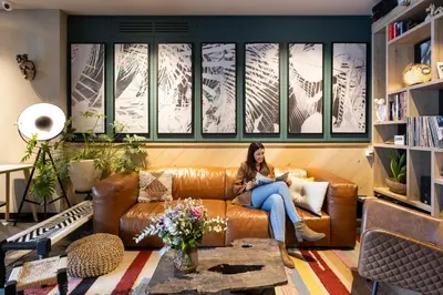 a woman sitting on a couch in a living room at Hotel Indigo Antwerp City Centre by IHG in Antwerp