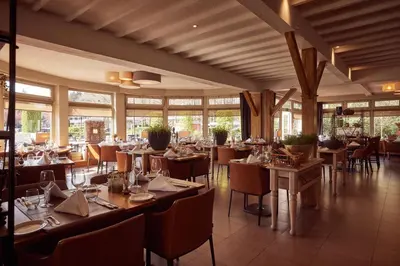 a dining room with tables and chairs and windows at Van der Valk Hotel Dennenhof in Brasschaat