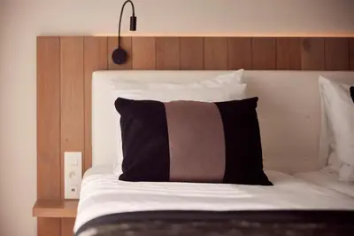 a bed with a black and brown pillow on it at Van der Valk Hotel Dennenhof in Brasschaat