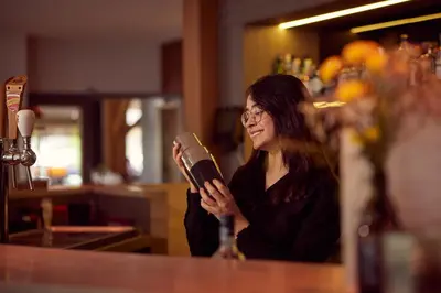 a woman standing at a counter holding a hair dryer at Van der Valk Hotel Dennenhof in Brasschaat